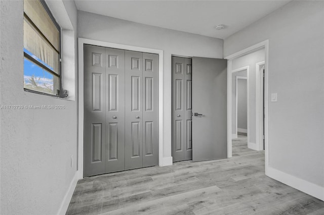 unfurnished bedroom featuring light hardwood / wood-style floors and two closets