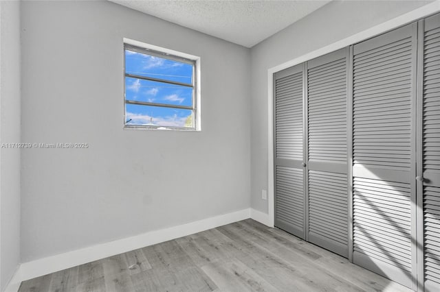 unfurnished bedroom with a textured ceiling, light hardwood / wood-style flooring, and a closet