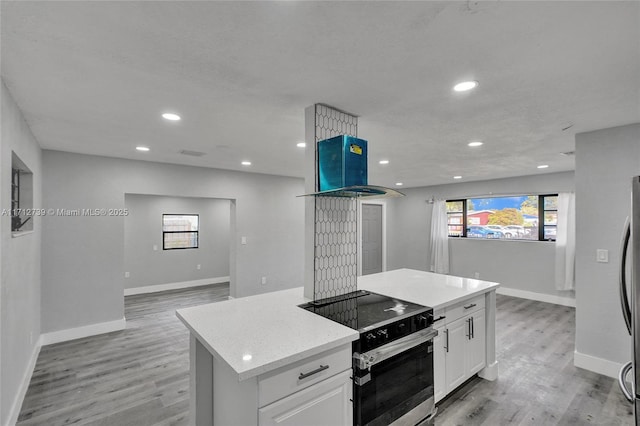 kitchen with white cabinets, light wood-type flooring, appliances with stainless steel finishes, a kitchen island, and island exhaust hood