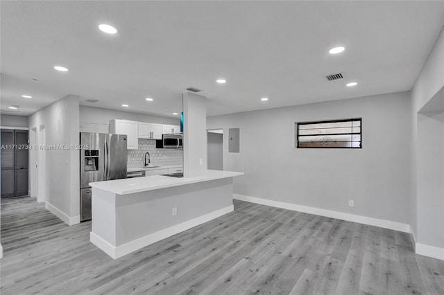 kitchen with white cabinetry, sink, light hardwood / wood-style flooring, decorative backsplash, and appliances with stainless steel finishes