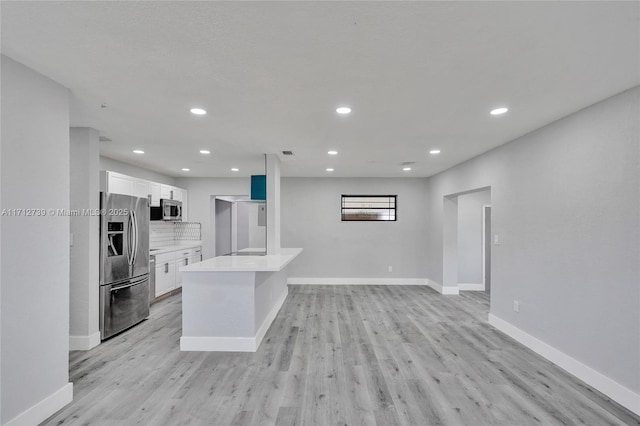 kitchen featuring decorative backsplash, appliances with stainless steel finishes, light hardwood / wood-style flooring, a center island, and white cabinetry