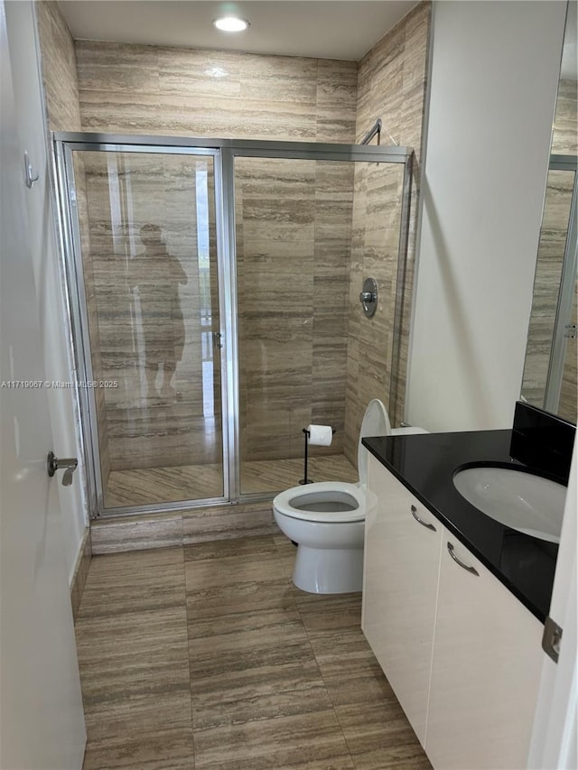 bathroom featuring tile patterned floors, vanity, toilet, and an enclosed shower