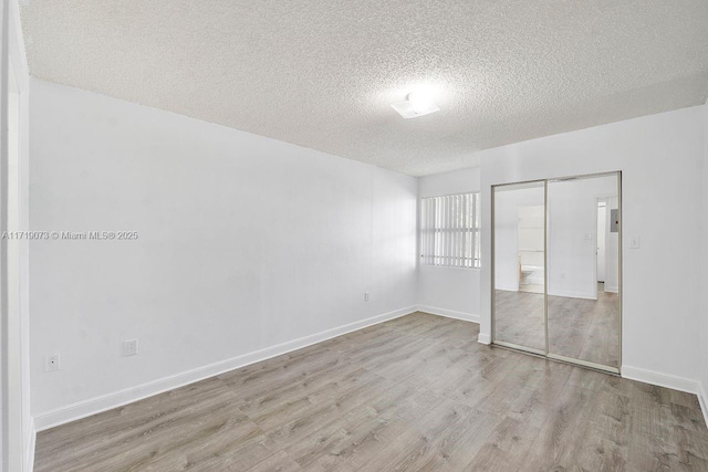 unfurnished bedroom with a closet, a textured ceiling, and light wood-type flooring