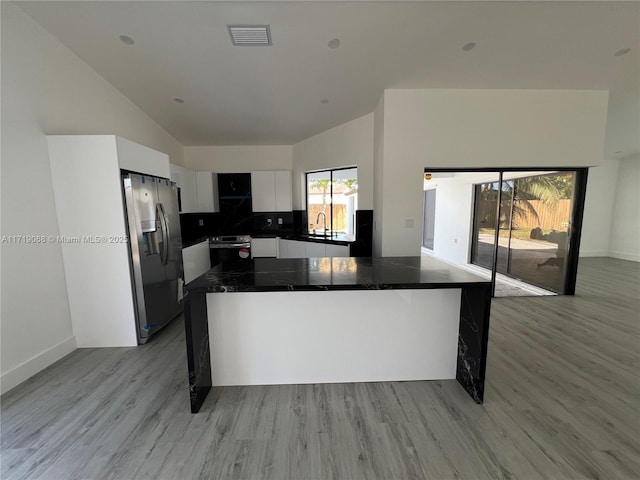 kitchen featuring light wood-type flooring, sink, white cabinets, stainless steel fridge with ice dispenser, and oven