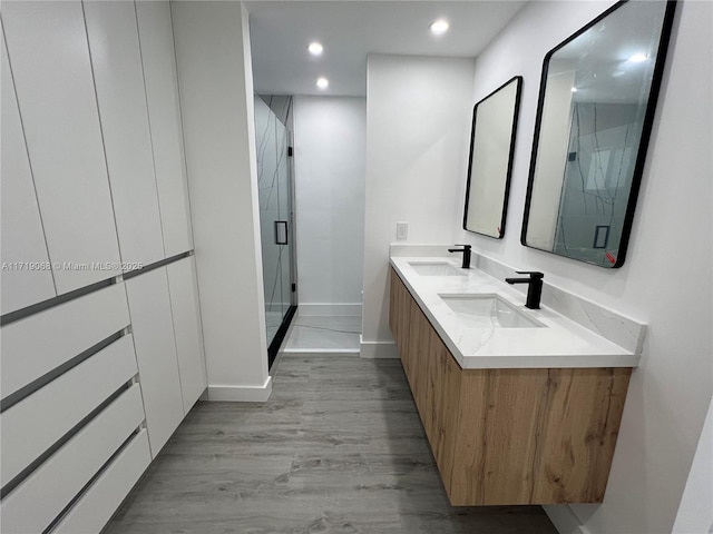 bathroom with hardwood / wood-style flooring, vanity, and a shower with shower door