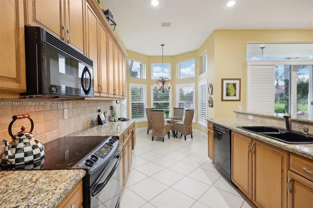 kitchen with black appliances, sink, hanging light fixtures, a notable chandelier, and a healthy amount of sunlight