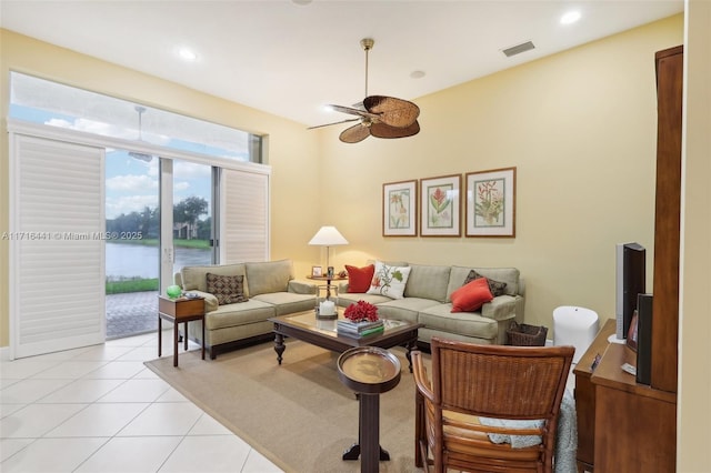 tiled living room with ceiling fan and a water view