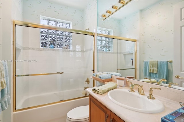 full bathroom featuring combined bath / shower with glass door, vanity, and toilet