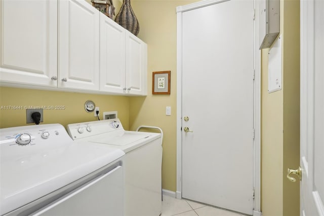 clothes washing area featuring washer and dryer, light tile patterned floors, and cabinets