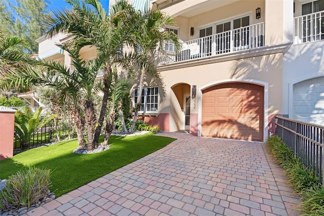 view of front of house featuring a balcony, a front yard, and a garage