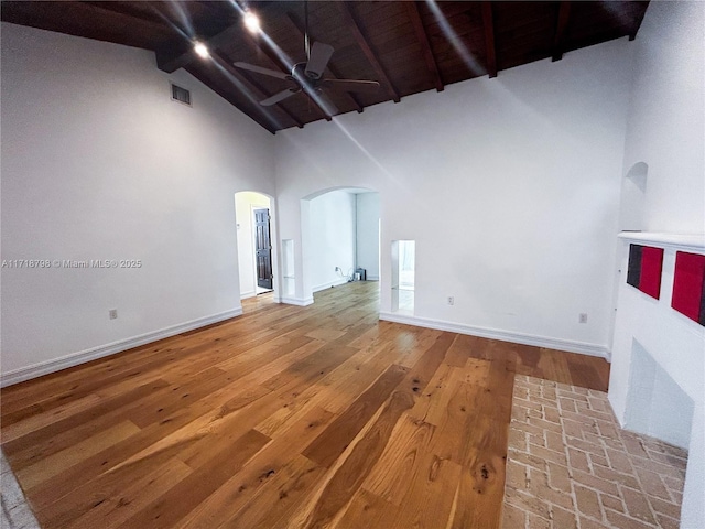 unfurnished living room with beam ceiling, high vaulted ceiling, ceiling fan, and hardwood / wood-style floors