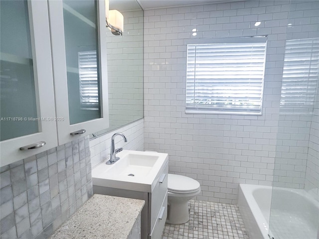 full bathroom with tile patterned flooring, tub / shower combination, toilet, vanity, and tile walls