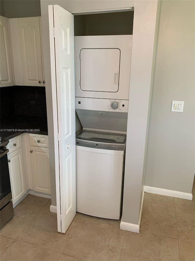 washroom with stacked washer and dryer and light tile patterned flooring