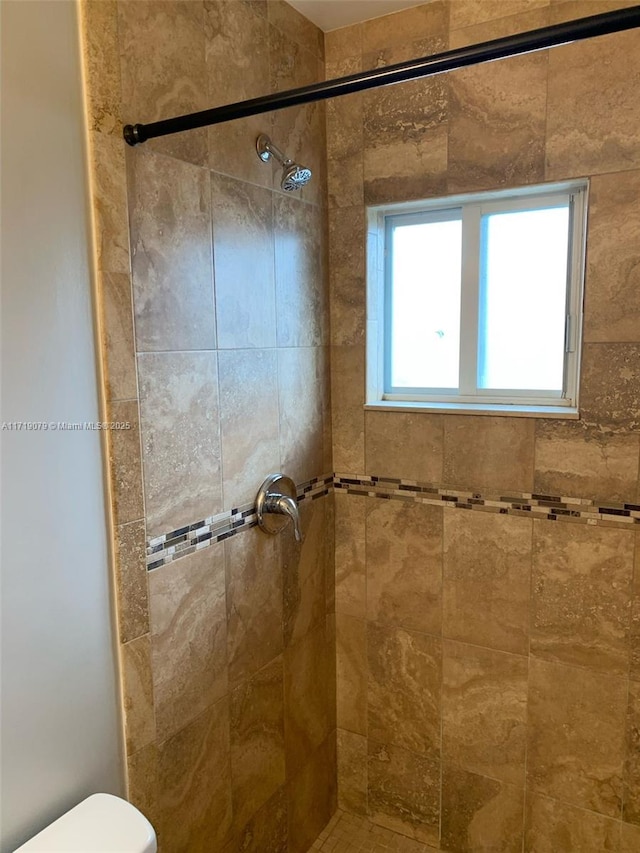 bathroom with a tile shower and toilet