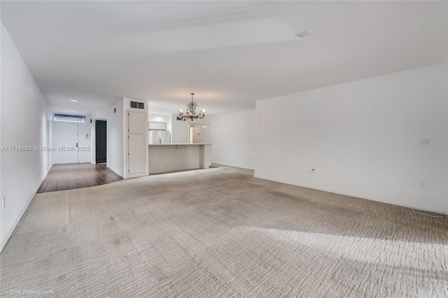 carpeted spare room with an inviting chandelier