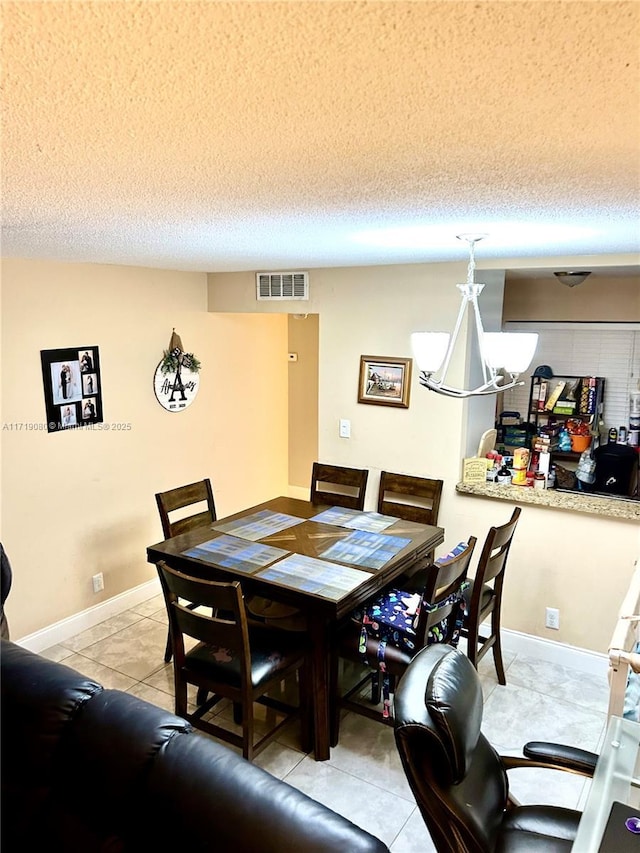 tiled dining area with a chandelier and a textured ceiling