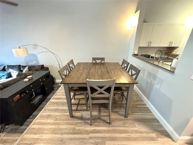 dining space featuring baseboards and light wood-style floors