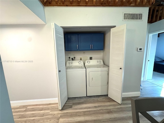 laundry area with light wood-type flooring, cabinets, and washer and dryer