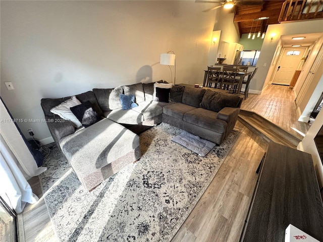 living area with high vaulted ceiling, wood finished floors, wood ceiling, and baseboards