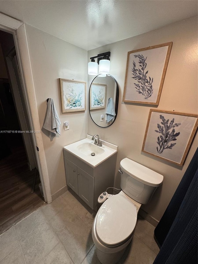 bathroom with baseboards, vanity, toilet, and tile patterned floors