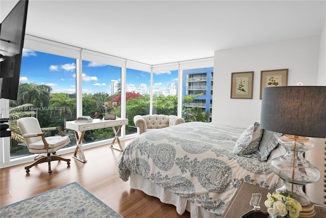 bedroom featuring multiple windows, wood-type flooring, and a wall of windows