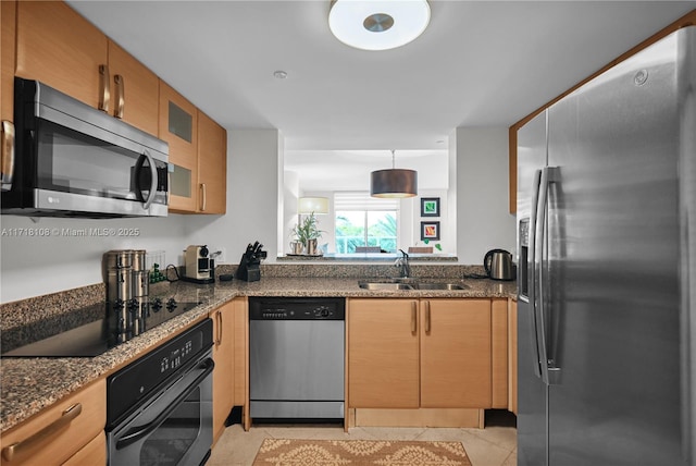 kitchen featuring black appliances, sink, dark stone countertops, decorative light fixtures, and light tile patterned flooring