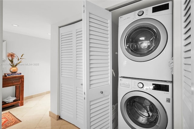 clothes washing area featuring light tile patterned floors and stacked washer and clothes dryer