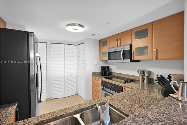 kitchen with dark stone countertops, light tile patterned floors, and stainless steel appliances