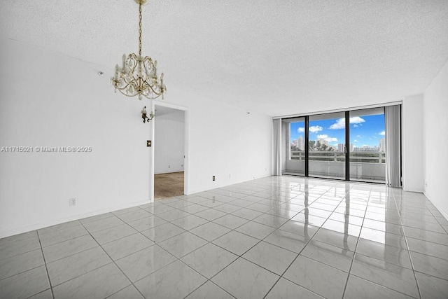 empty room with light tile patterned floors, a textured ceiling, floor to ceiling windows, and a notable chandelier