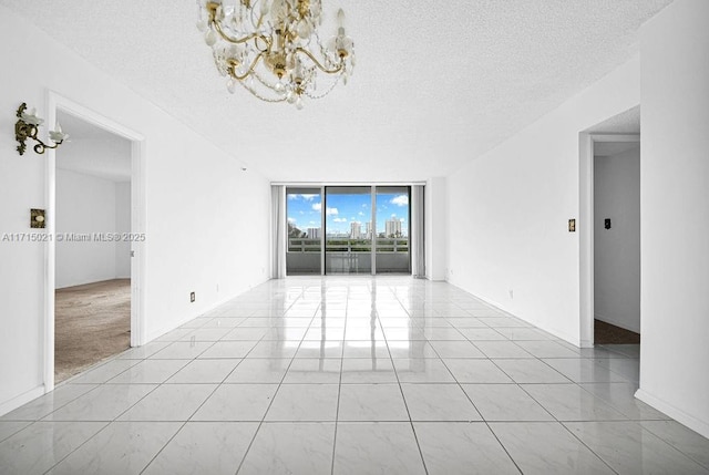 spare room featuring floor to ceiling windows, light tile patterned floors, a textured ceiling, and a notable chandelier