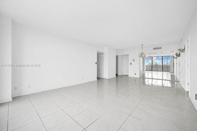 empty room with a notable chandelier and light tile patterned flooring