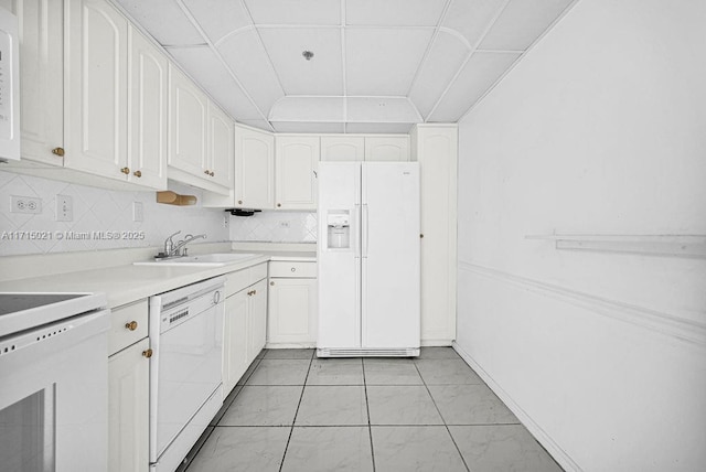 kitchen featuring white appliances, sink, light tile patterned floors, tasteful backsplash, and white cabinetry