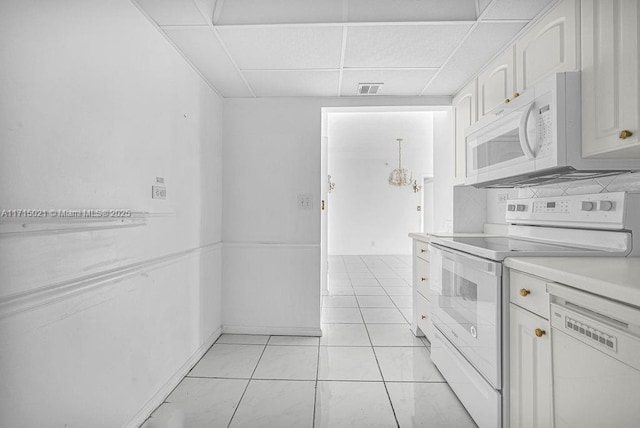 kitchen with light tile patterned floors, white cabinets, a drop ceiling, and white appliances