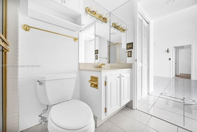 bathroom with tile patterned floors, vanity, a textured ceiling, and toilet