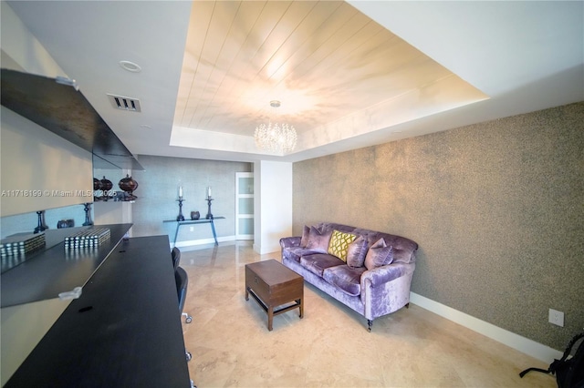 living room featuring a raised ceiling, built in shelves, and a notable chandelier