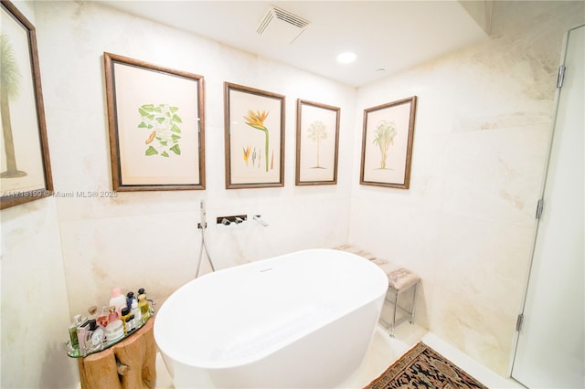 bathroom with a bathing tub and tile walls