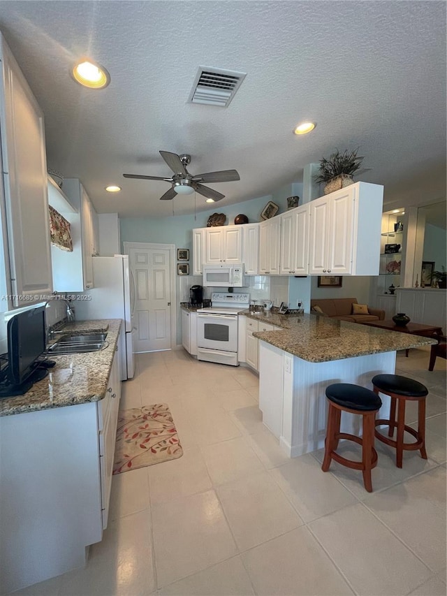 kitchen with white cabinets, white appliances, kitchen peninsula, and sink