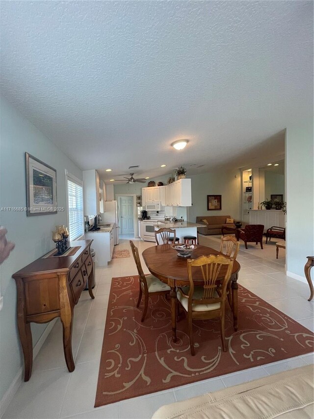 tiled dining room with a textured ceiling and ceiling fan