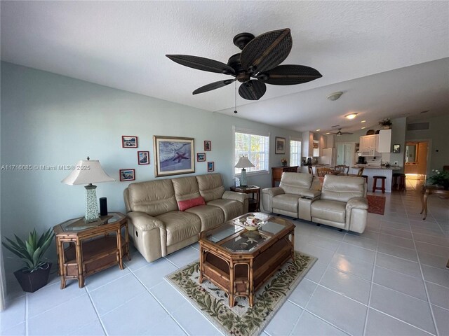 living room with a textured ceiling, ceiling fan, light tile patterned floors, and lofted ceiling