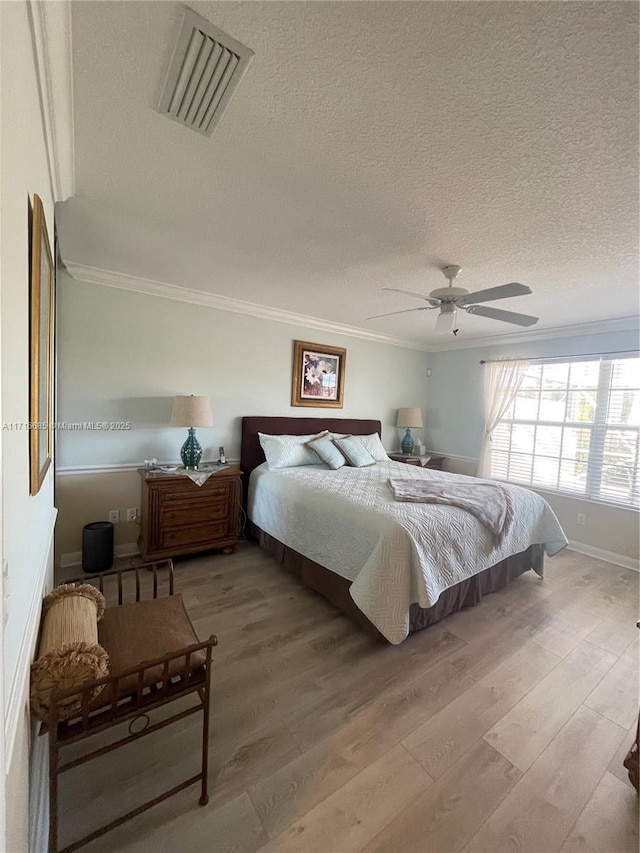 bedroom featuring hardwood / wood-style flooring, ceiling fan, ornamental molding, and a textured ceiling