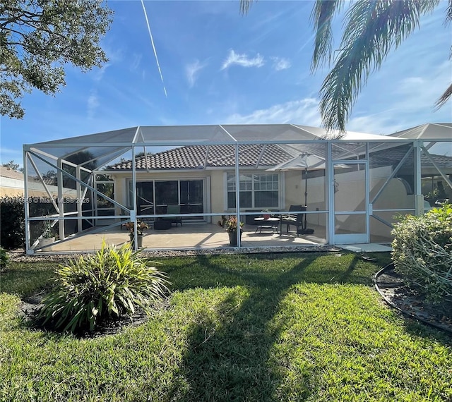 back of house featuring glass enclosure, a yard, and a patio