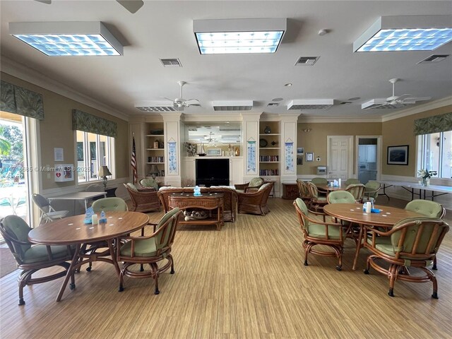 dining space featuring built in shelves, ceiling fan, and crown molding