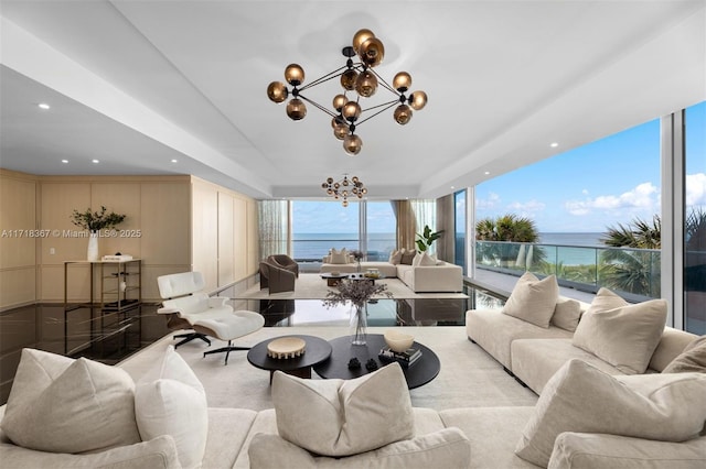 living room featuring floor to ceiling windows, a water view, an inviting chandelier, and plenty of natural light