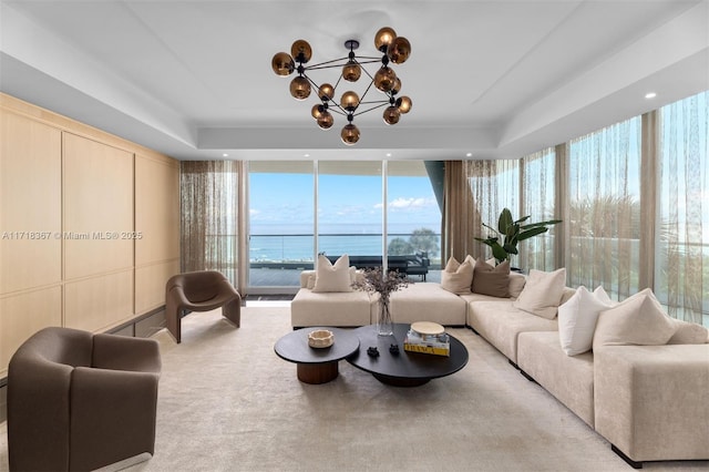 carpeted living room featuring a water view and a chandelier