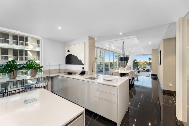 kitchen featuring white cabinets, expansive windows, and sink