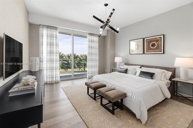 bedroom featuring a chandelier, access to exterior, a wall of windows, and light hardwood / wood-style flooring