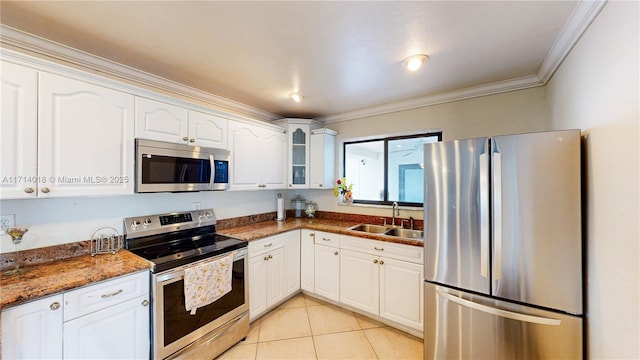 kitchen featuring sink, white cabinetry, appliances with stainless steel finishes, ornamental molding, and dark stone counters