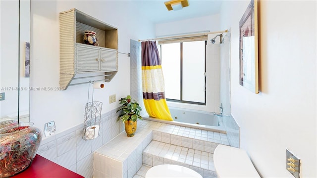 bathroom with toilet and tiled tub