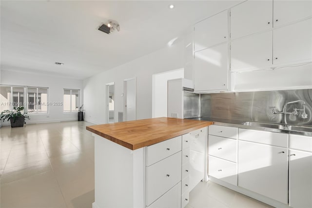 kitchen featuring butcher block countertops, sink, and white cabinets