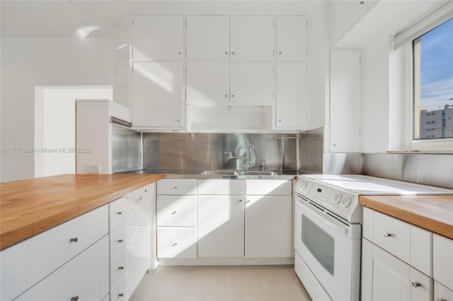 kitchen featuring wood counters, sink, light tile patterned floors, electric range, and white cabinetry